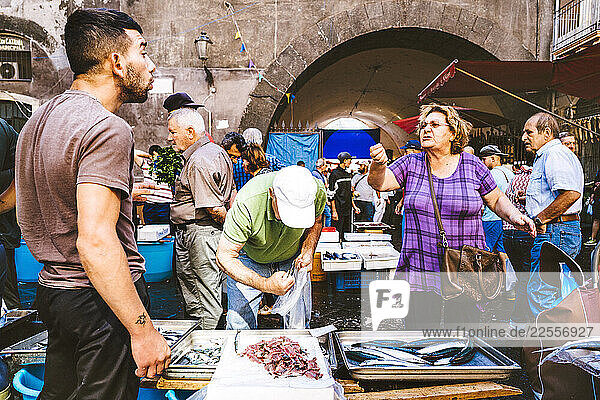 A Fish Monger and his customer haggle over the price of the daily catch in the fish market of Catania  Sicily.