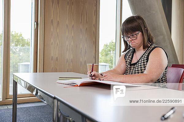 Woman with Down Syndrome writing in office