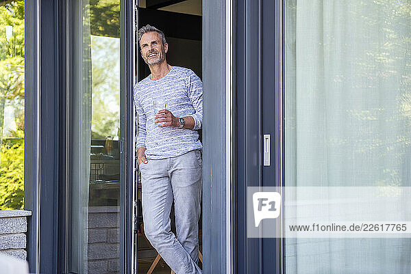 Smiling man standing in doorway at home during daytime
