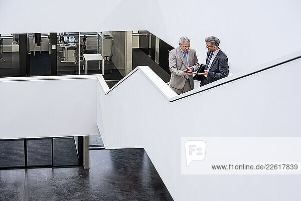 Business professionals discussing strategy on a staircase in a modern office