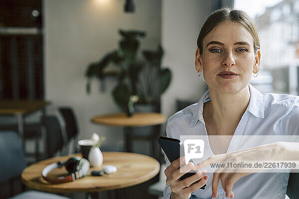 Woman in a café using a smartphone for remote work