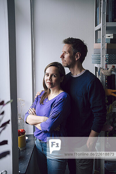 A couple standing together at home  looking out the window in a moment of connection and contemplation