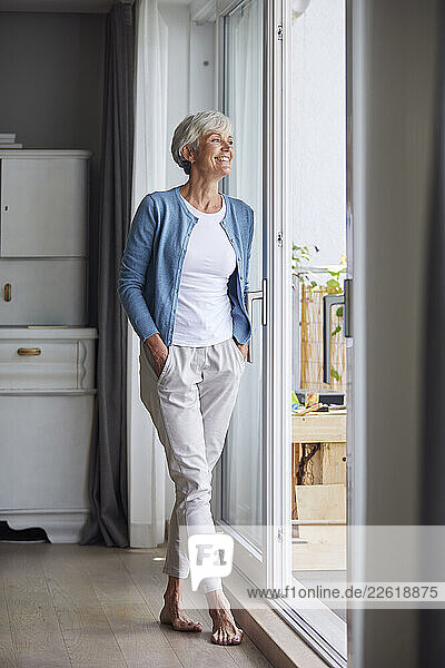 Happy woman enjoying time at home looking out the window
