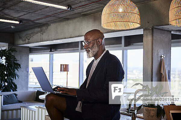 Mature man working on laptop while sitting at home