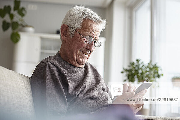 Senior man at home enjoying using a smartphone