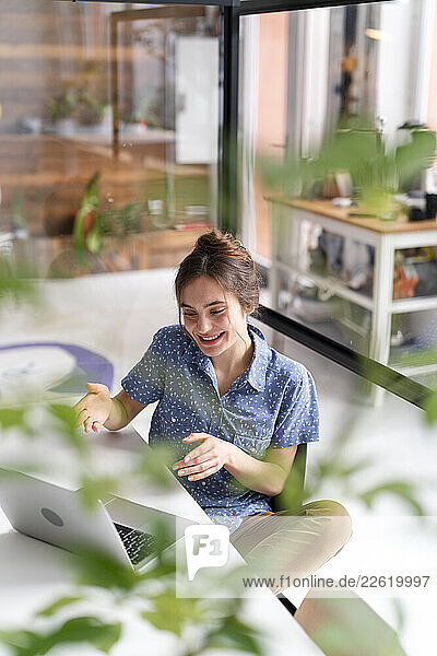 Woman in a home office talking happily during a video call