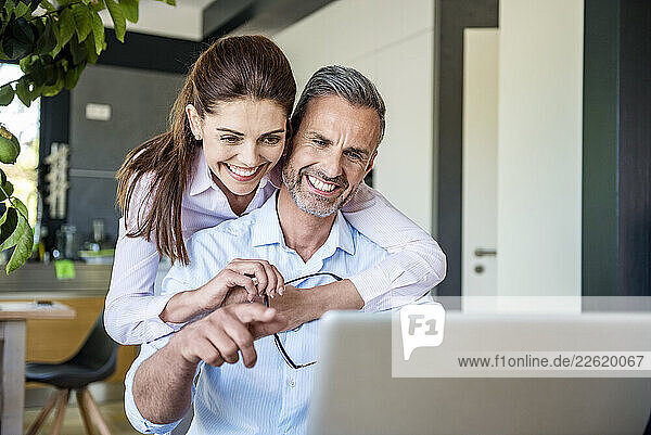 Smiling couple working together at home with a laptop