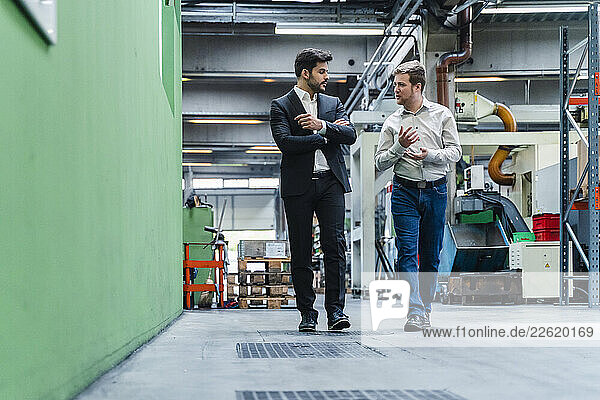Male entrepreneur and manager walking while discussing in industry