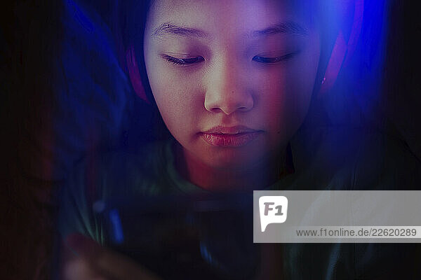 Girl with headphones using a smartphone in neon light