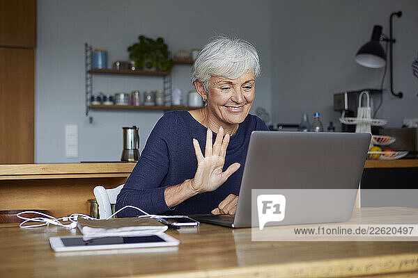 Woman at home using laptop for a video call in the kitchen