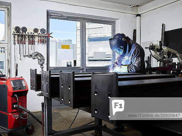 Welding technician performing welding work with protective equipment in his workshop