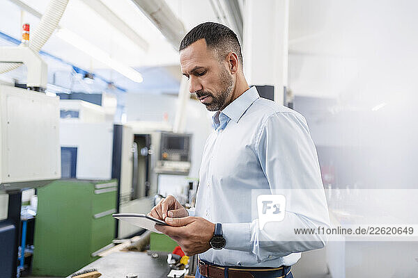 Businessman using tablet in factory hall