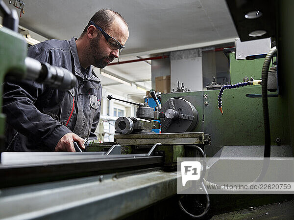 Metal construction technician working at a lathe in his workshop