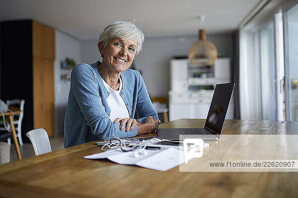 Woman at home using a laptop and looking satisfied