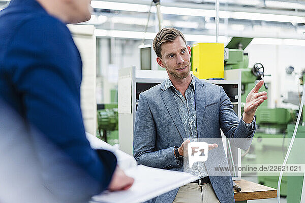 Male professional talking about manufacturing equipment with engineer in factory