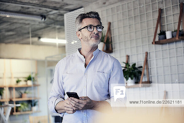 Entrepreneur with mobile phone looking away
