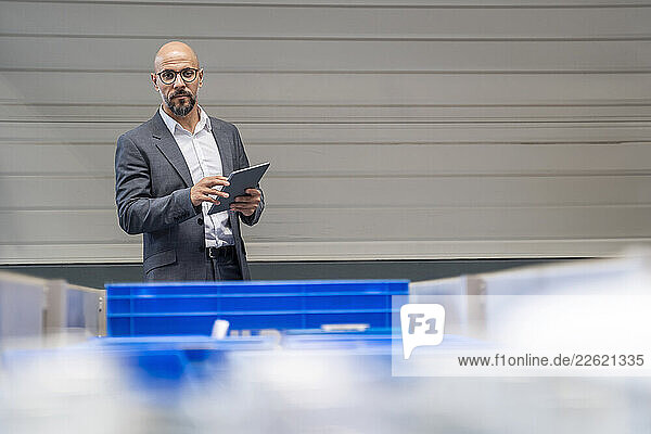 Businessman in a production hall using a tablet