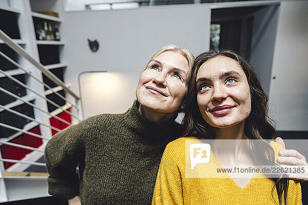Mother and daughter daydreaming together at home