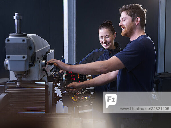 Smiling engineers using CNC machine at factory