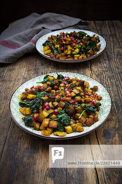 Crispy potato  chickpeas  spinach  and pomegranate seeds on a dark wooden table