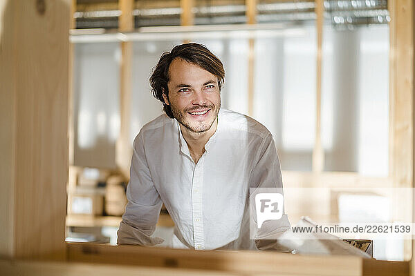 Portrait of smiling businessman in wooden open-plan office