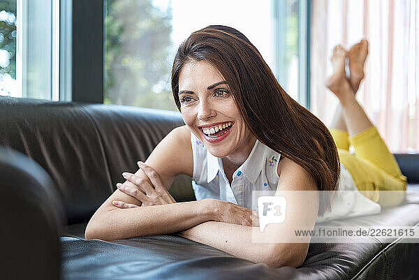 Smiling woman relaxing on a sofa at home during the day