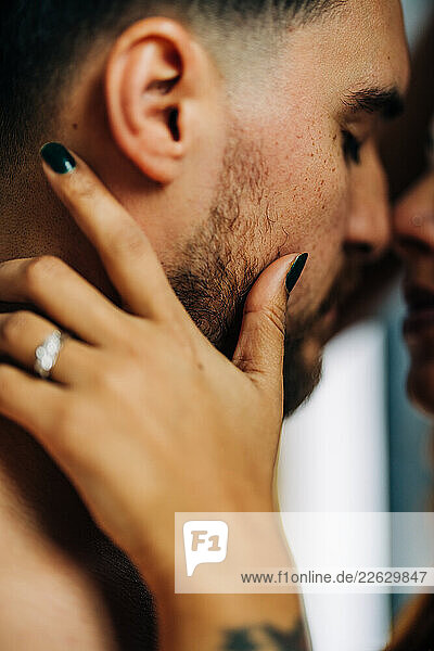Close-up of couple touching faces tenderly before a kiss