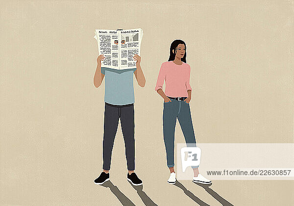 Woman standing next to man peeking through holes of newspaper