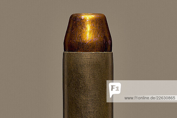Close up of single .44 magnum bullet cartridge on brown background