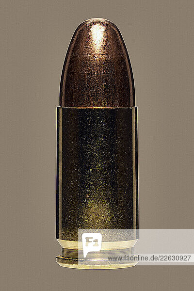 Close up studio shot 9 x 19mm bullet on brown background