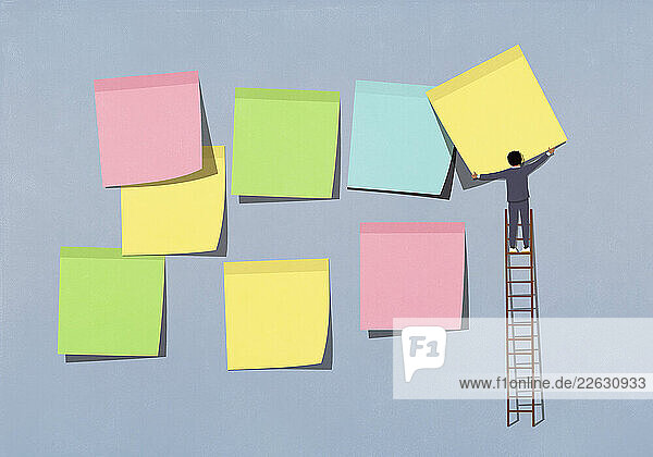 Businessman on ladder arranging multicolor adhesive notes on blue background