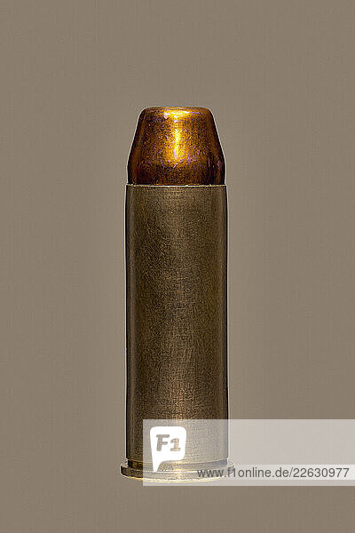 Close up of single .44 Magnum bullet cartridge on brown background