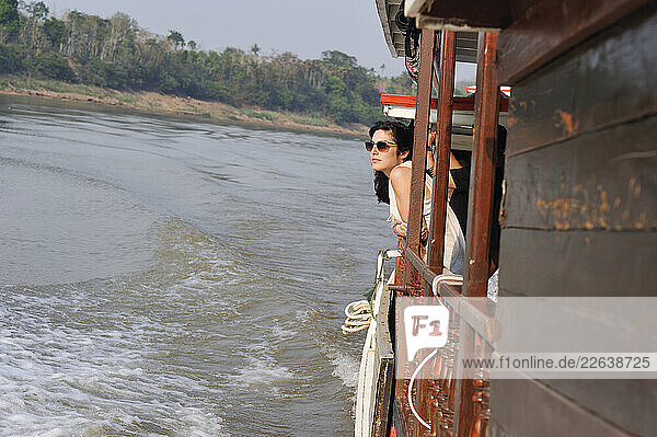 Young woman standing at the railing of The Luang Say Lodge and Cruises cruise boat on Mekong River  Oudomxay Province  Laos