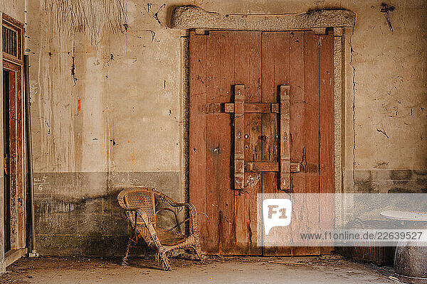 Old door in Hong Kong in an abadoned building with a wicker chair  Hong Kong  China