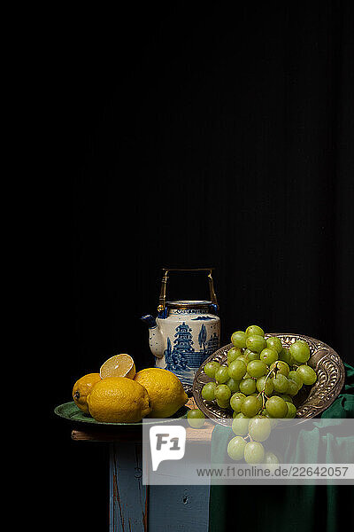 Table with lemons and grapes with a black background