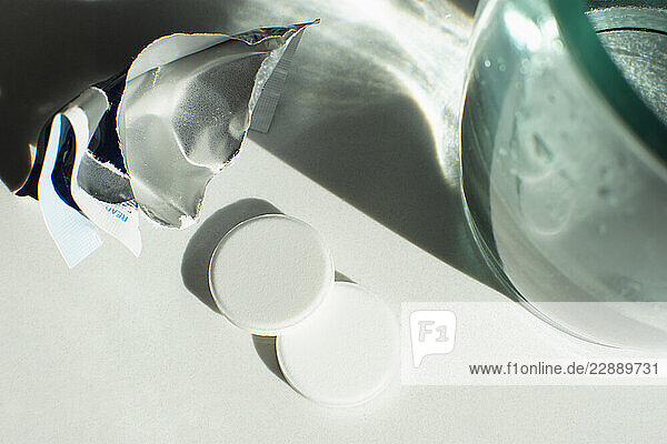 Close-up of effervescent antacid tablets next to glass of water