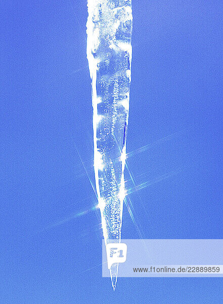 Icicle reflecting sunlight against clear blue sky