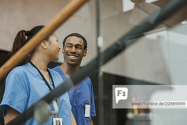 Happy male and female wearing medical scrubs talking with each other