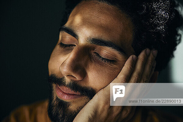 Smiling man with eyes closed leaning on palm of hand