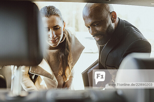 Female customer checking out car features with salesman