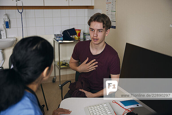 Patient discussing with doctor sitting at desk in clinic