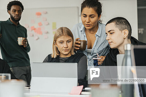 Multiracial business entrepreneurs planning strategies on laptop while working in tech hub
