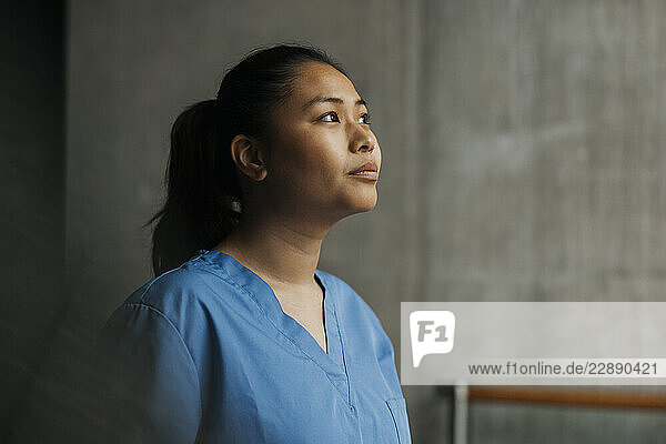 Contemplative young female physician looking away