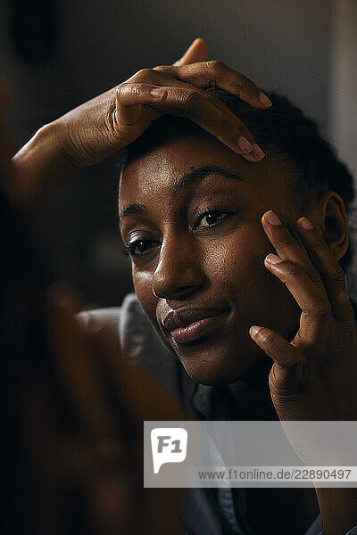 Woman doing skin care routine while looking in mirror at bathroom