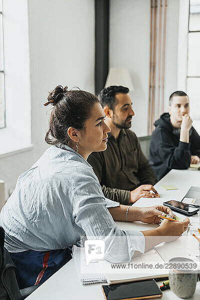 Concentrated businesswoman sitting at desk with colleague for meeting in startup office