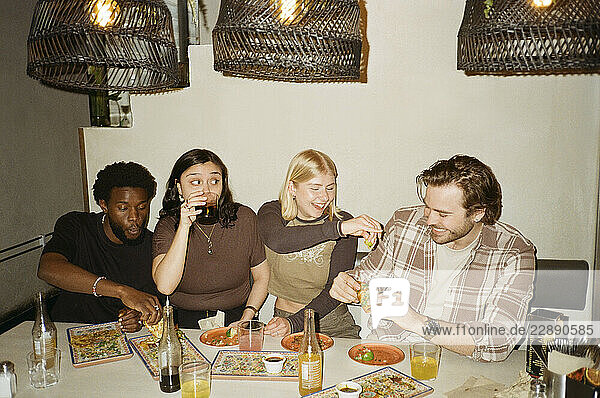 Group of happy friends spending leisure time while eating tacos at fast food restaurant