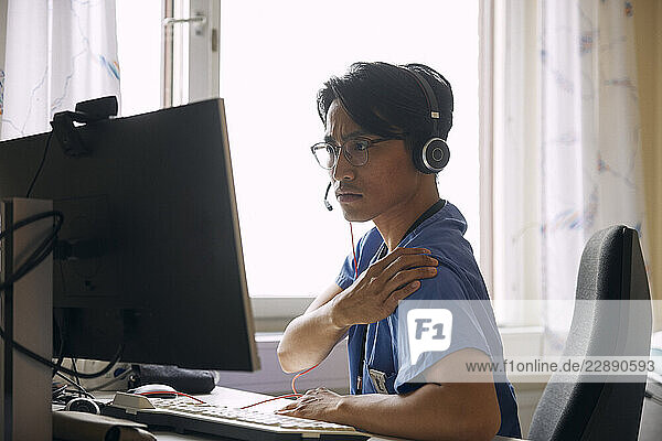 Doctor wearing headset and explaining over video call on computer