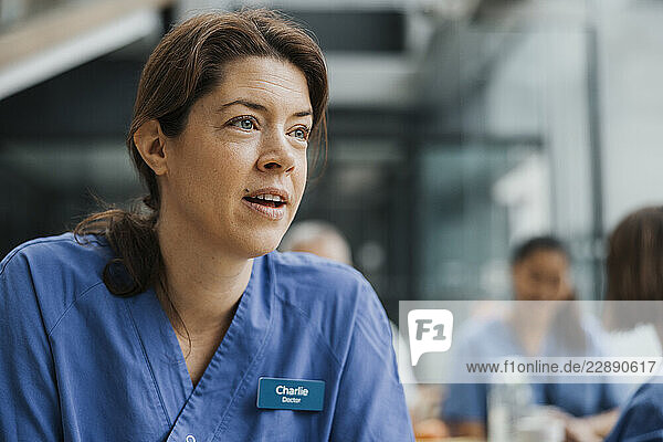 Mature female nurse talking in cafeteria at hospital
