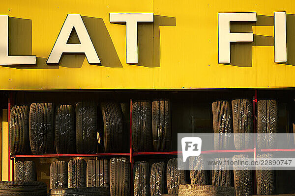 Tires stacked in a row under a bold yellow sign with large white letters. New York City  USA