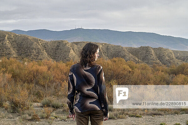 Woman gazes at desert landscape with rolling hills under a cloudy sky. Near Malaga  Spain